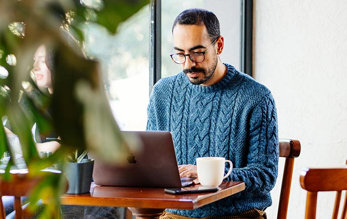 Man using laptop in a cafe with plants.